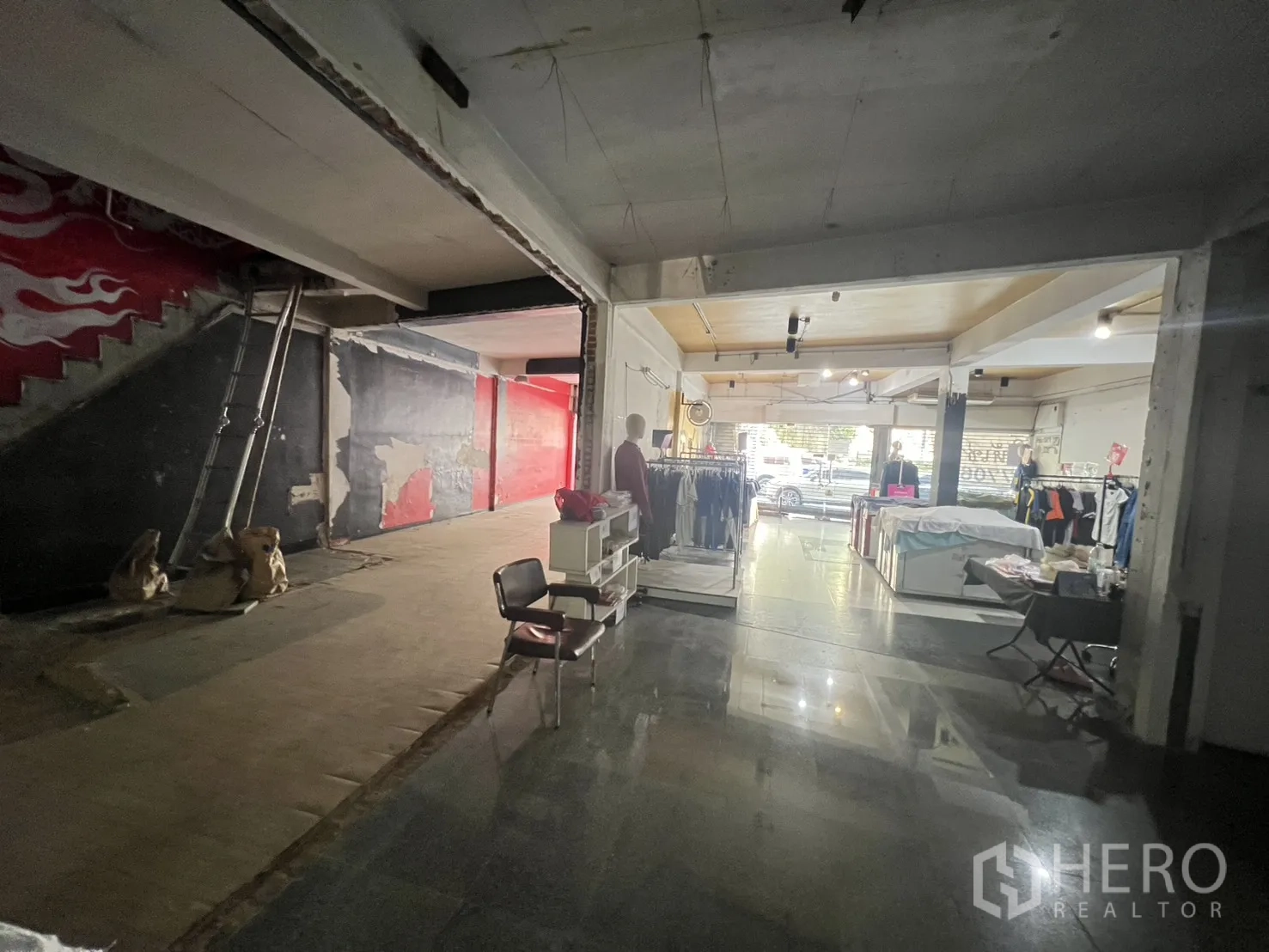 Shophouse for rent in Khlong Toei, Bangkok - Connected retail floor with glossy tile zone and display racks beside a renovation area.
