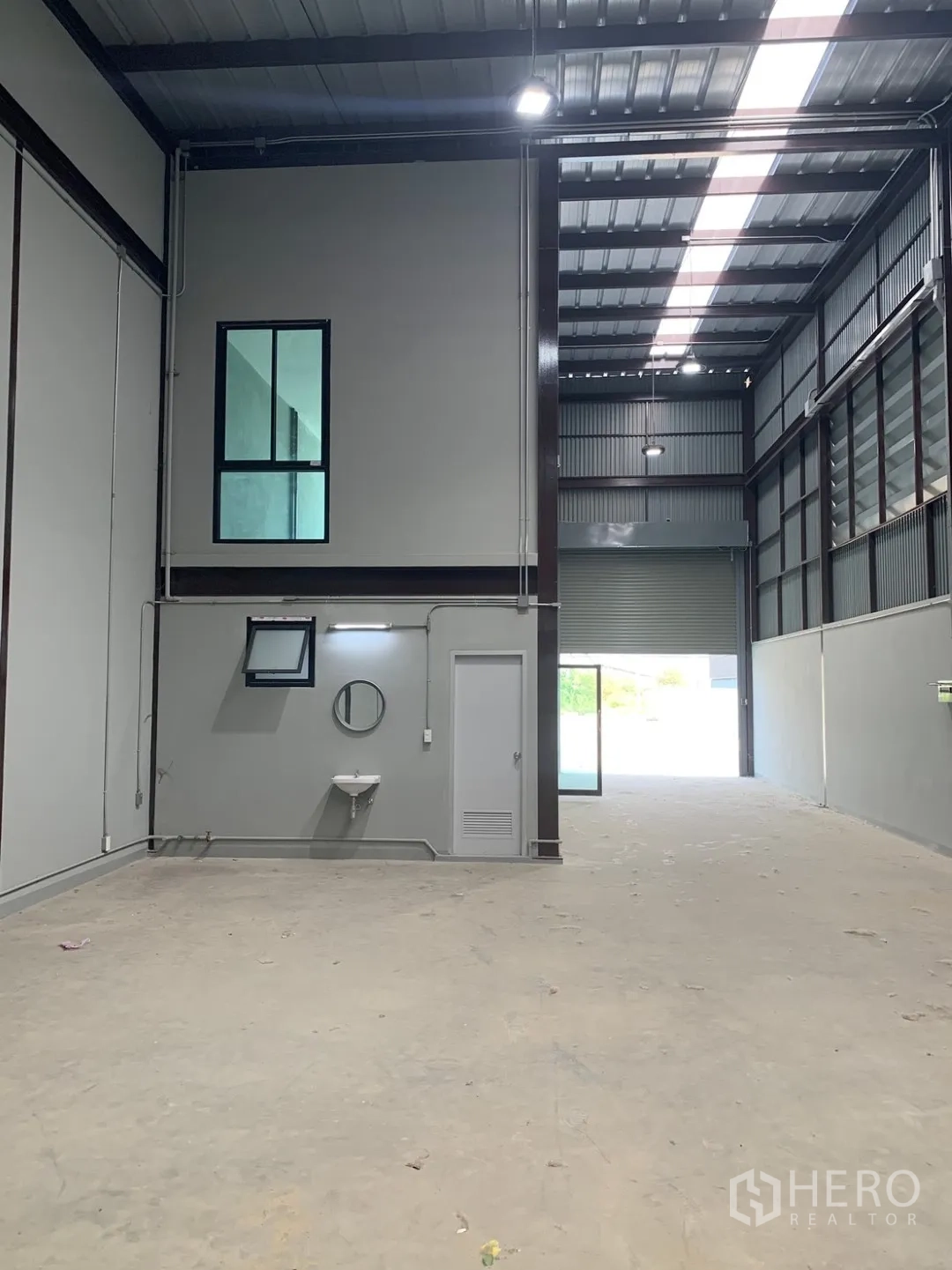 仓库 for rent in Bang Phli, Samut Prakan - 高挑库区带屋顶采光带、洗手盆与卷闸门入口。