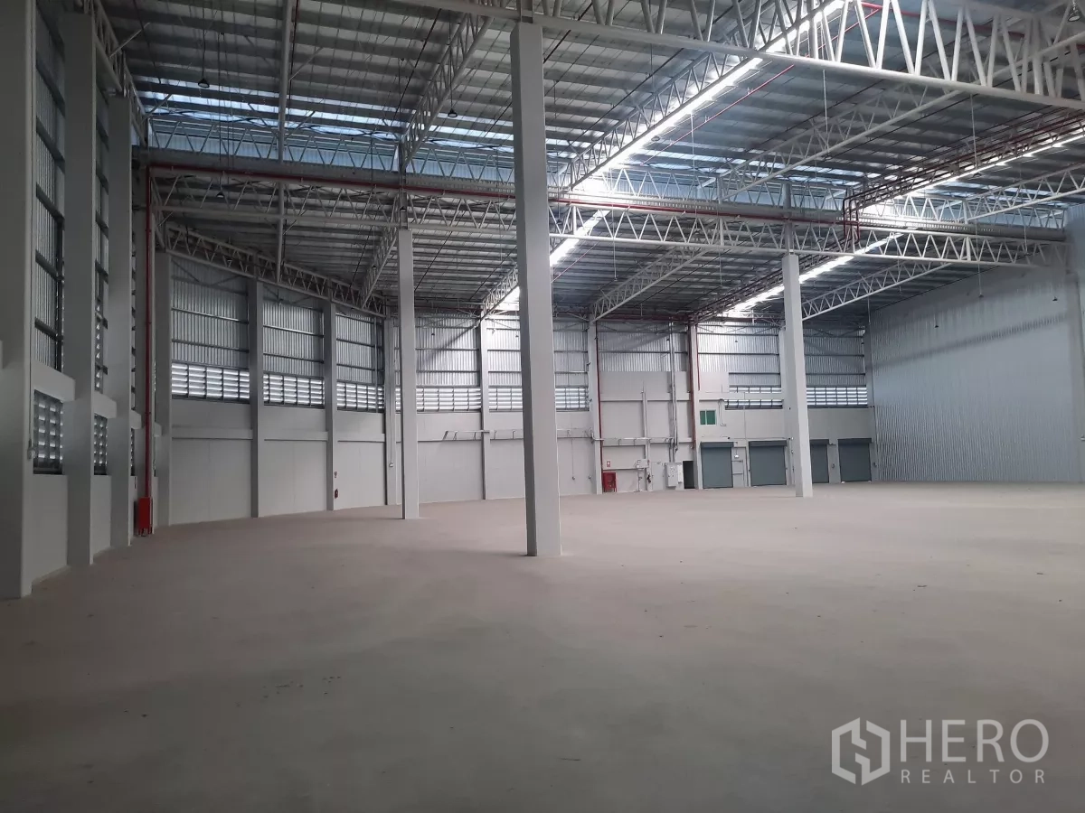 工厂 出租在Bang Lamung, Chon Buri - 高挑仓库内部，钢桁架屋顶与卷帘装卸门
