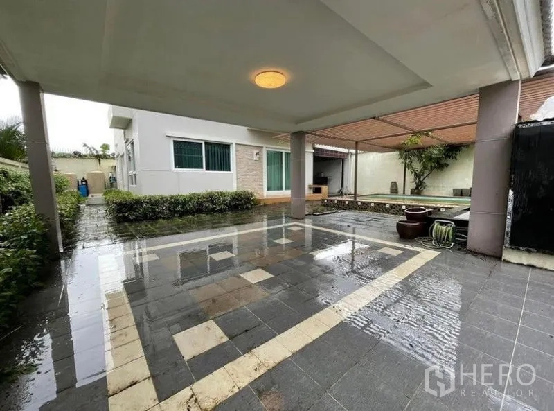 Detached House for sale in Bang Phli, Samut Prakan - Covered patio and driveway next to landscaped yard and the pool area.