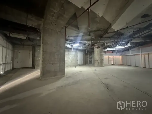 Retail Space for rent - Industrial-style space with multiple columns, rough walls and ceiling-mounted utilities and sprinklers.