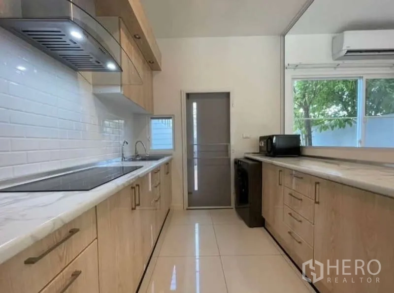 Townhouse for rent in Prawet, Bangkok - Galley kitchen with long countertops, window, and side door