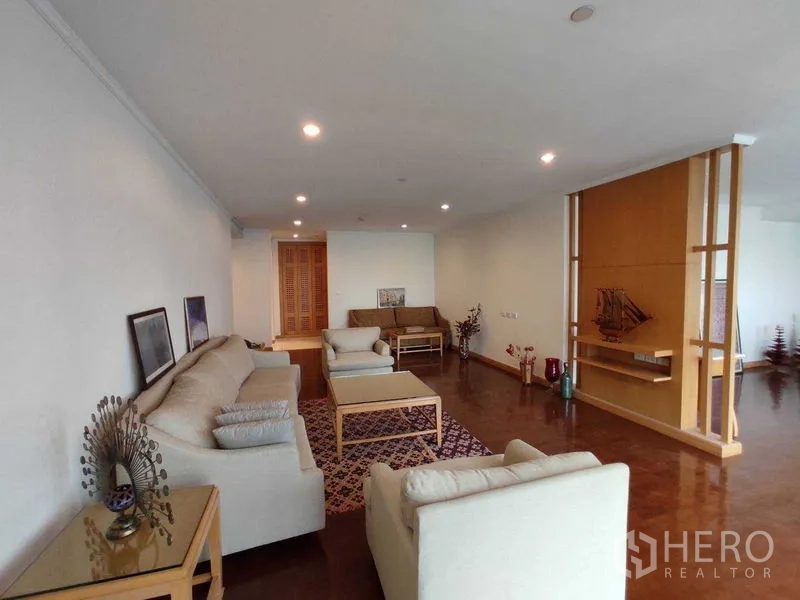 Condominium for rent in Khlong Toei, Bangkok - Large living room with multiple sofas, open partition and polished hardwood floors.
