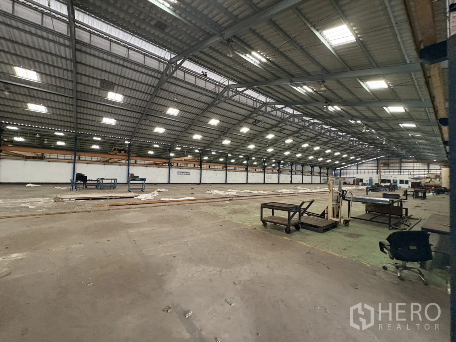 Factory for rent in Phra Pradaeng, Samut Prakan - Large hall with equipment racks and skylights along the roof.