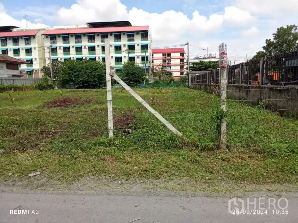 地 出租在Khan Na Yao, Bangkok - 入口立柱与铁丝门通向空地，背景可见公寓建筑。