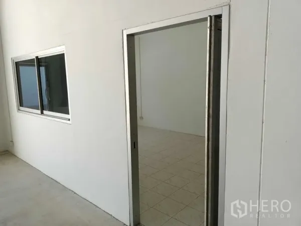 Warehouse for rent in Suan Luang, Bangkok - Entrance to a tiled office room with an aluminum sliding window inside the warehouse.
