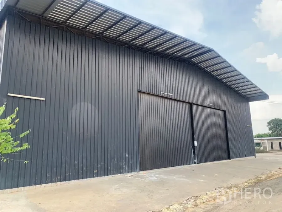 Warehouse for rent in Khan Na Yao, Bangkok - Modern black metal-clad warehouse exterior with wide sliding doors and a covered loading area.