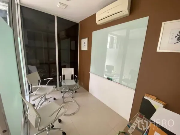 Home Office for rent in Wang Thonglang, Bangkok - Compact glass meeting room with round table, white chairs and a wall whiteboard.