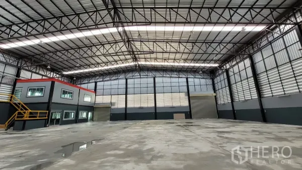 Factory for rent or sale in Phanat Nikhom, Chon Buri - High-roof warehouse floor with skylights and dual roller shutters for loading.