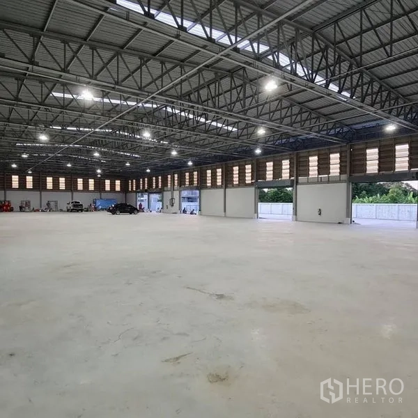 Warehouse for rent in Prawet, Bangkok - Spacious warehouse interior featuring roller shutter doors opening to the yard.