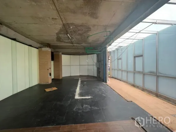Retail Space for rent in Watthana, Bangkok - Shell-condition retail interior with concrete ceiling, dark tile flooring, and a frosted glass wall.