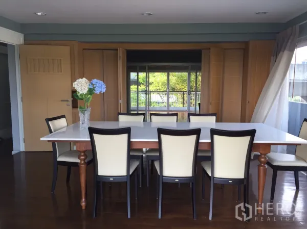 Home Office for rent or sale in Suan Luang, Bangkok - Spacious dining room with eight chairs, wooden flooring, and large windows to the balcony.