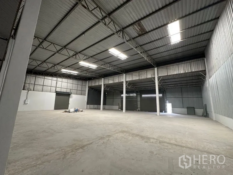 Warehouse for rent in Khlong Luang, Pathum Thani - Spacious warehouse interior with high steel truss roof, skylights, and smooth concrete floor.