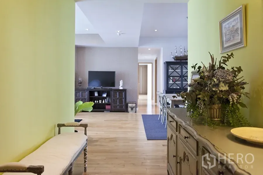 Condominium for rent in Khlong Toei, Bangkok - Bright living and dining area with wooden floors, green accent wall, and TV console.