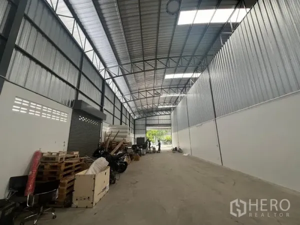Warehouse for rent in Khlong Sam Wa, Bangkok - Long interior aisle facing the entrance with roller shutter, metal cladding walls, skylights and ventilation blocks.