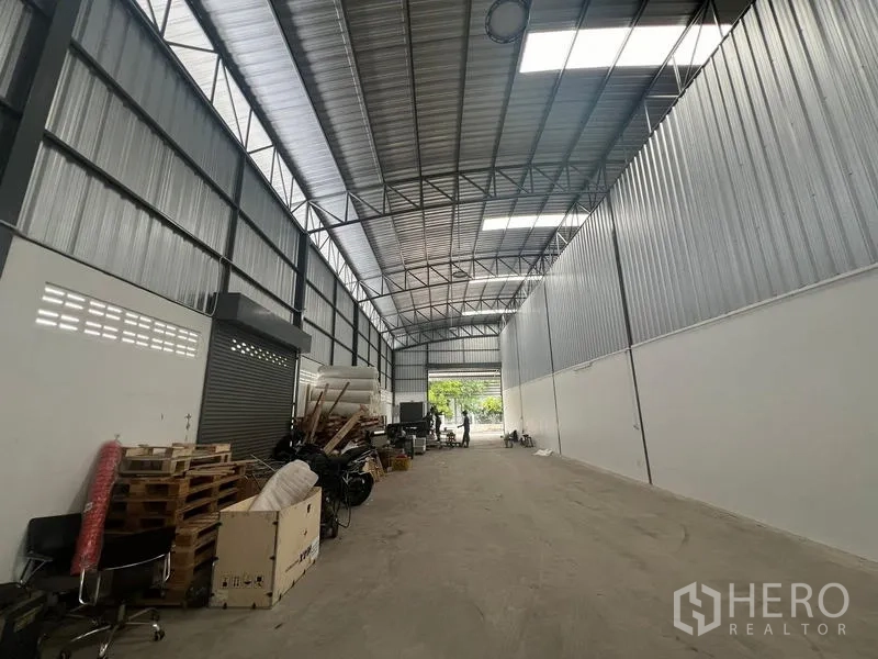 Warehouse for rent in Khlong Sam Wa, Bangkok - Long interior aisle facing the entrance with roller shutter, metal cladding walls, skylights and ventilation blocks.