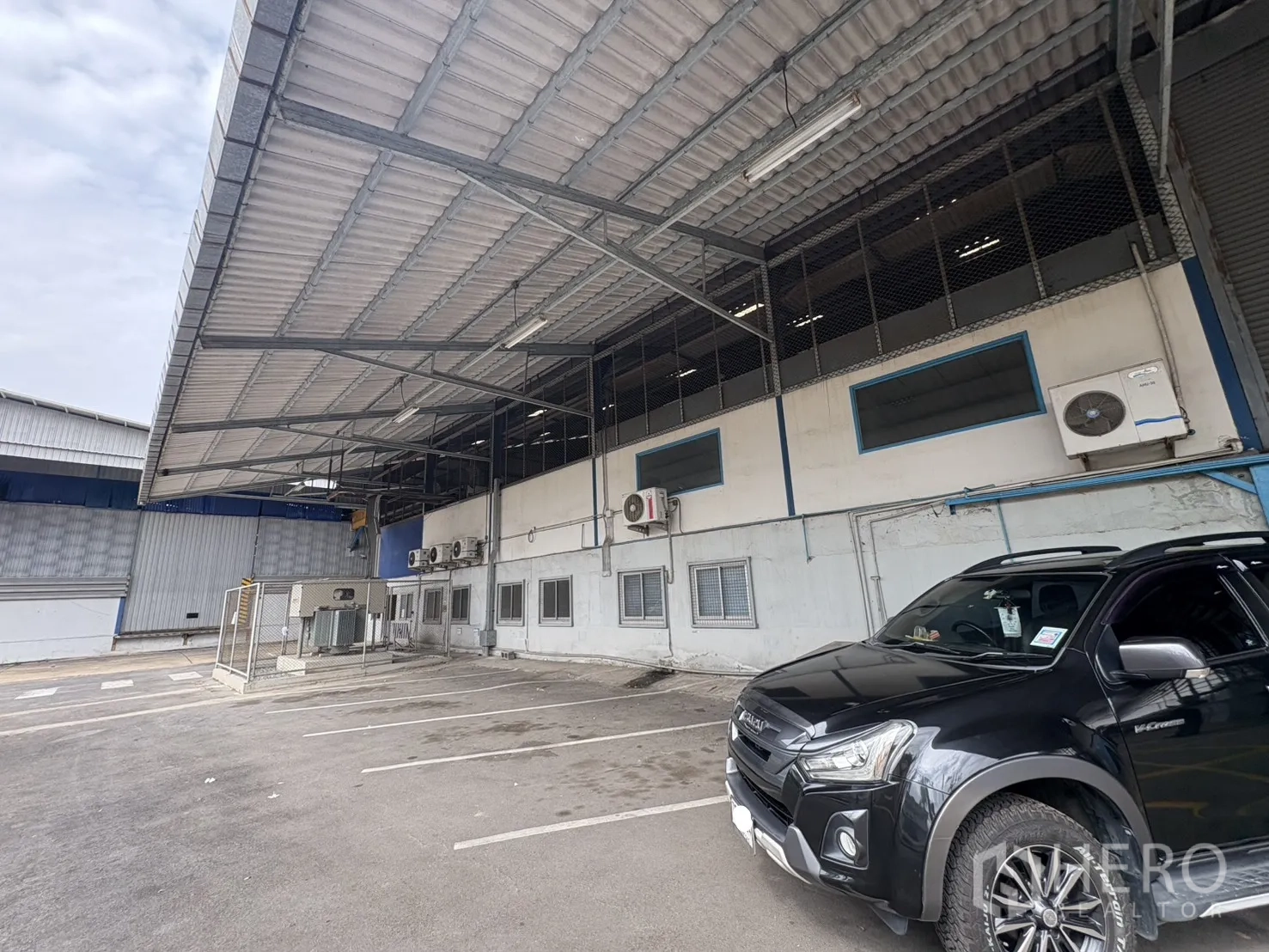 Factory for rent in Phra Pradaeng, Samut Prakan - Covered loading area with air‑conditioning units and parking bays.