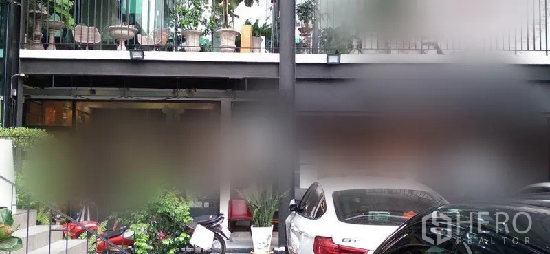 Retail Space for rent in Watthana, Bangkok - Two-storey commercial building facade with balcony planters and ground-floor parking with cars.