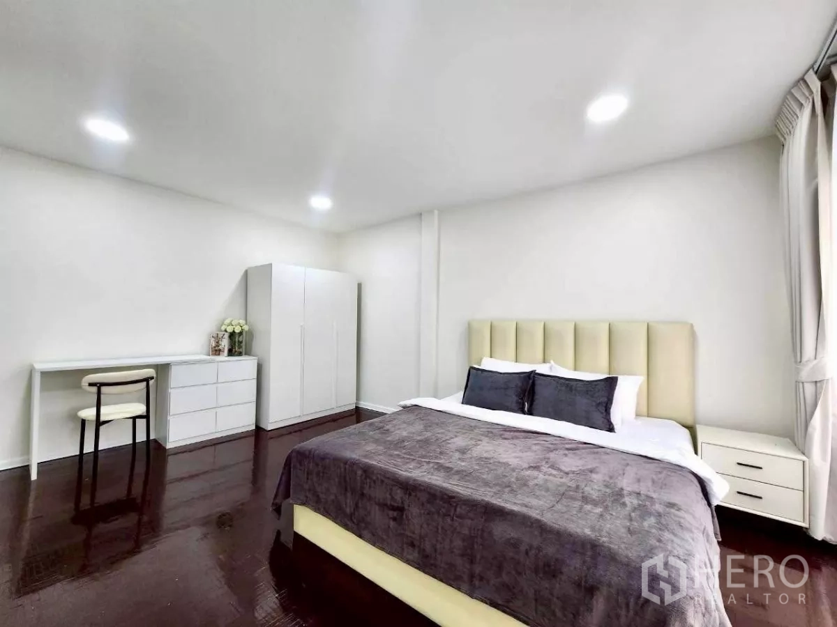 ทาวน์เฮาส์ ให้เช่าในHuai Khwang, Bangkok - ห้องนอนแขกกว้าง เตียงคิงส์ พื้นไม้สีเข้ม ตู้เสื้อผ้า และโต๊ะทำงาน
