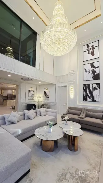 Detached House for rent in Prawet, Bangkok - Double-volume living room with crystal chandelier, sectional sofas and marble coffee tables.