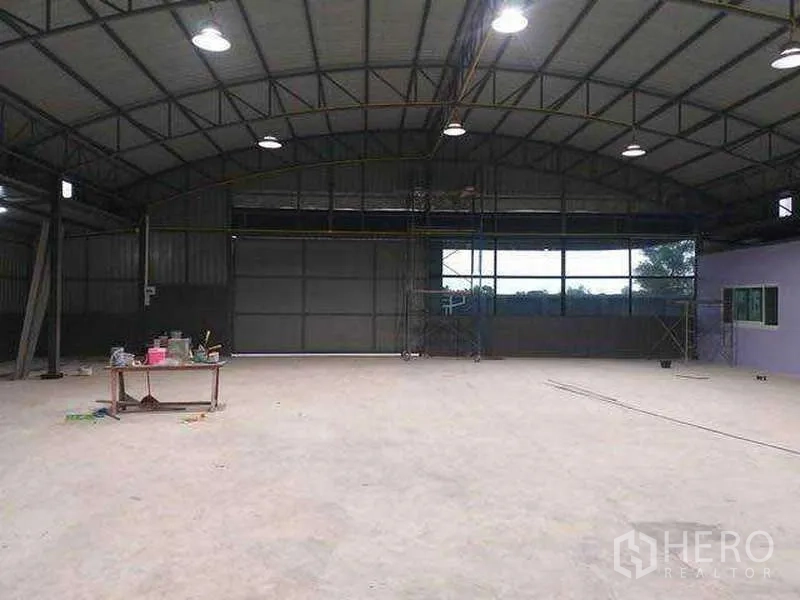 Warehouse for rent in Khlong Sam Wa, Bangkok - Open‑plan warehouse interior with high arched steel roof, windows and bright high‑bay lights.