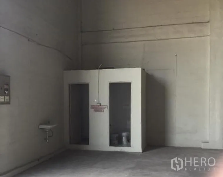Warehouse for rent in Khlong Luang, Pathum Thani - Two simple restroom cubicles with a sink in the warehouse corner.