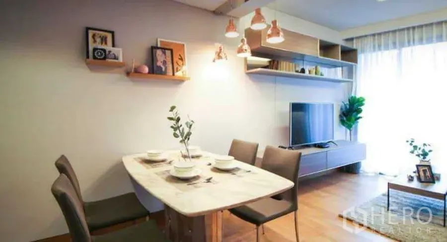 Condominium for rent or sale in Khlong Toei, Bangkok - Bright dining and living area with marble table, pendant lights, floating shelves, TV unit, wood flooring and a large window.