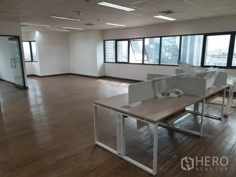 Office Space for rent in Watthana, Bangkok - Open-plan office with wood flooring, large windows and city views, partial workstations and bright ceiling lights.