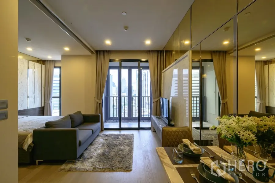 公寓 出租在Watthana, Bangkok - 开放式起居与卧室，落地阳台门、城市景观与镜面墙的餐区。