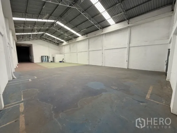 Warehouse for rent in Bang Phli, Samut Prakan - Spacious open-plan warehouse interior with a high steel-truss roof, skylight panels, white walls and durable concrete floor.