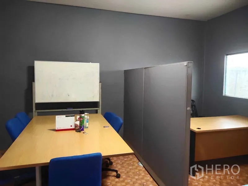 Warehouse for sale in Lam Luk Ka, Pathum Thani - Meeting room with table, blue chairs, whiteboard, and workstations.
