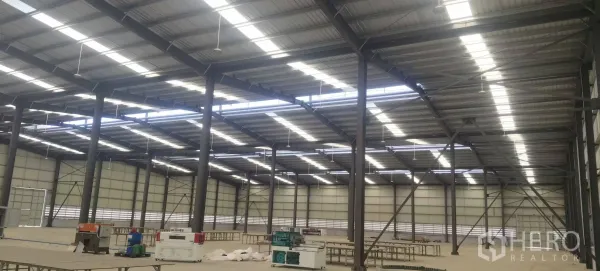 Factory for rent in Plaeng Yao, Chachoengsao - Expansive factory floor with steel columns, high metal roof, skylight panels, and work tables.