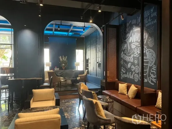 Retail Space for rent in Watthana, Bangkok - Lounge-style seating area with marble floors, arched alcoves, chalkboard mural wall, and a mix of sofas and tables in a modern retail interior.