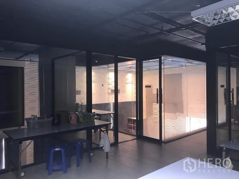 Retail Space for rent in Khlong Toei, Bangkok - Retail interior with glass-partitioned rooms, exposed ceiling, and a worktable area.