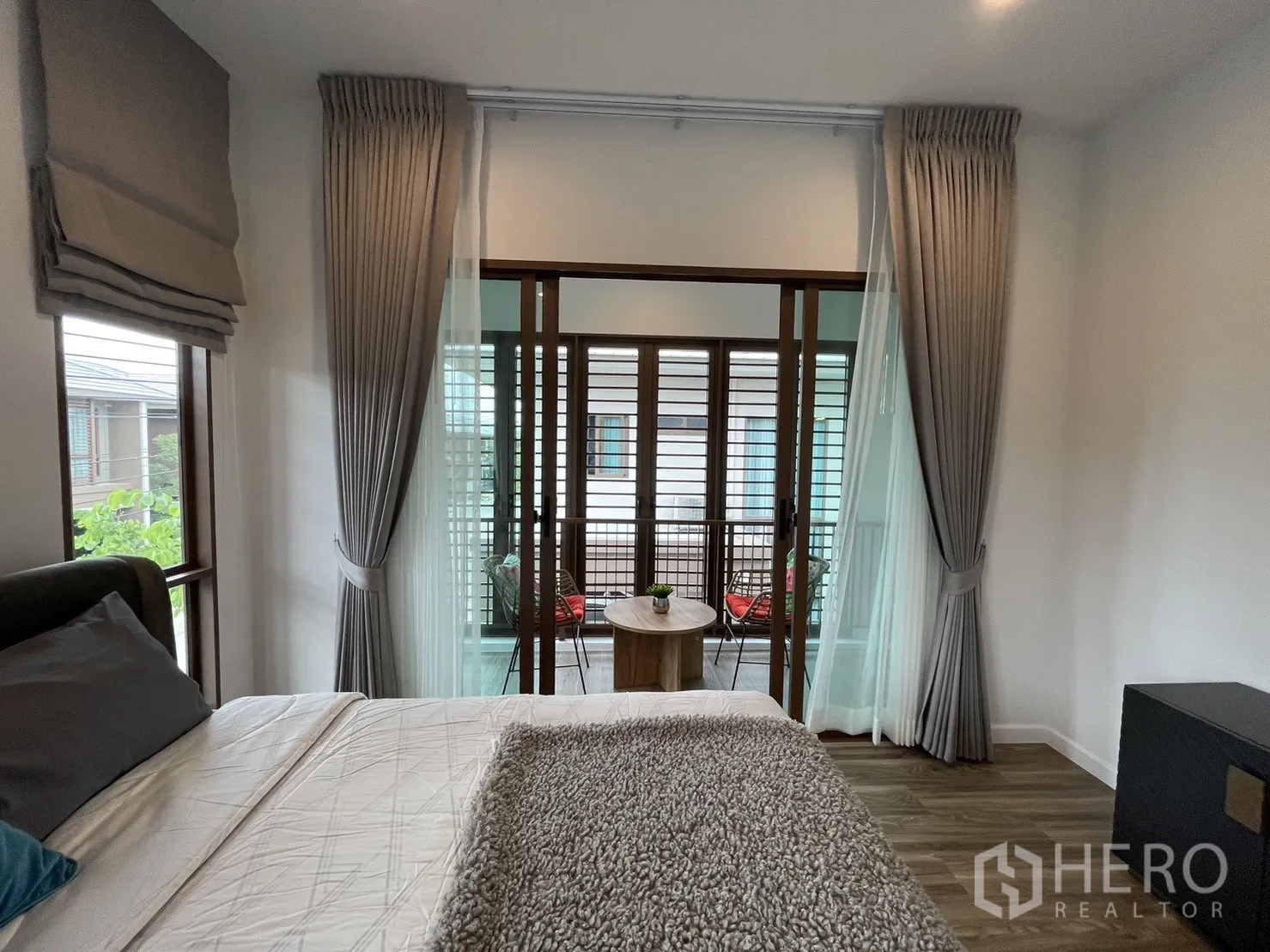 Detached House for rent in Bang Kapi, Bangkok - Master bedroom opening to a screened balcony with sliding doors and curtains.