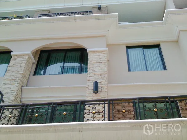 Townhouse for rent in Khlong Toei, Bangkok - Elegant multi-storey townhouse facade with stone cladding, arched windows and wrought‑iron balconies in Bangkok.