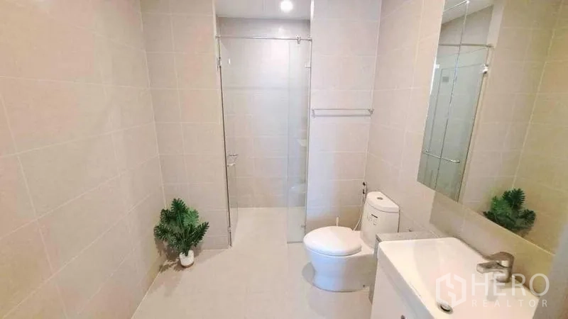 Condominium for rent or sale in Pathum Wan, Bangkok - Clean bathroom with glass-enclosed shower, vanity and toilet.