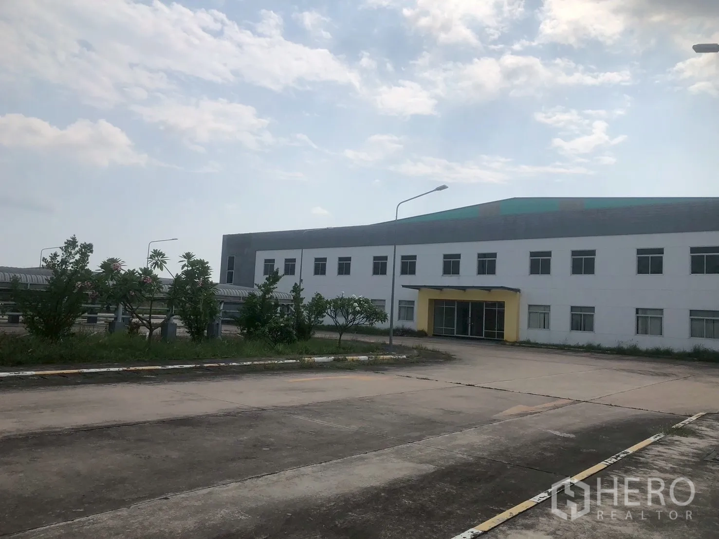 工厂 for rent in Pluak Daeng, Rayong - 现代低层工厂外观，前方为车道、绿化与中央入口雨棚。