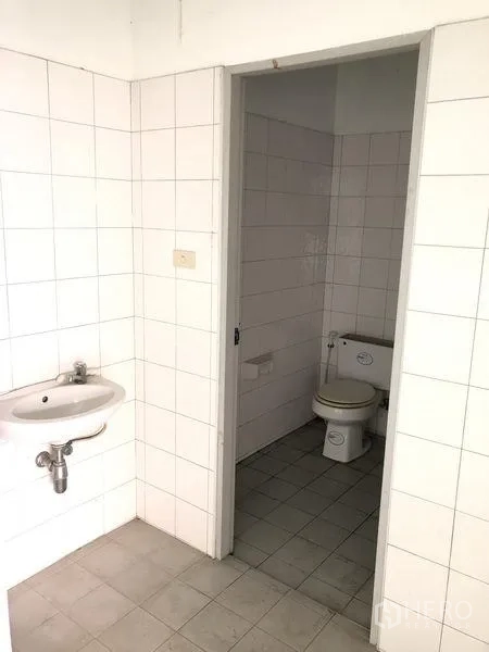 Factory for rent in Pathum Thani - Simple tiled restroom with sink and toilet inside the factory.