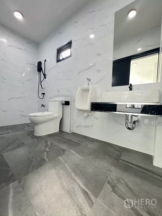 Warehouse for sale in Lam Luk Ka, Pathum Thani - Clean modern restroom with toilet, urinal, vanity and marble-look wall tiles.