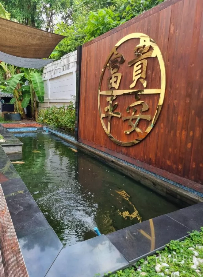 Detached House for rent in Bang Kapi, Bangkok - Garden koi pond with a wooden feature wall and gold emblem.