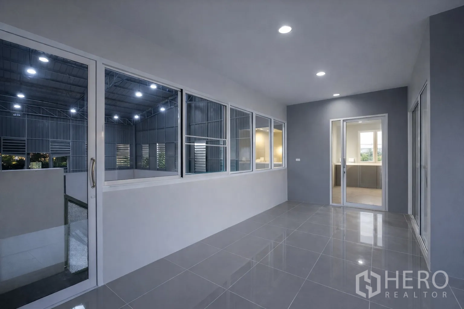 Warehouse for rent in Bang Kapi, Bangkok - Glass-walled mezzanine corridor overlooking the warehouse hall with tiled floors and ceiling lights.