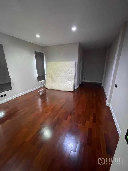 Detached House for sale in Mueang Samut Prakan, Samut Prakan - Spacious bedroom with wooden flooring and recessed lights, featuring side windows.
