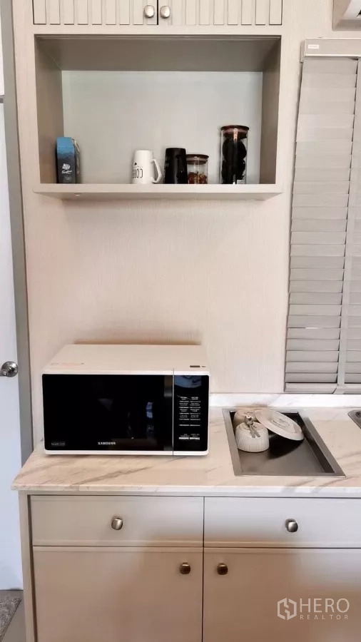 Townhouse for rent in Bang Phli, Samut Prakan - Compact kitchen corner with marble-look countertop, sink and a microwave on built-in cabinetry.