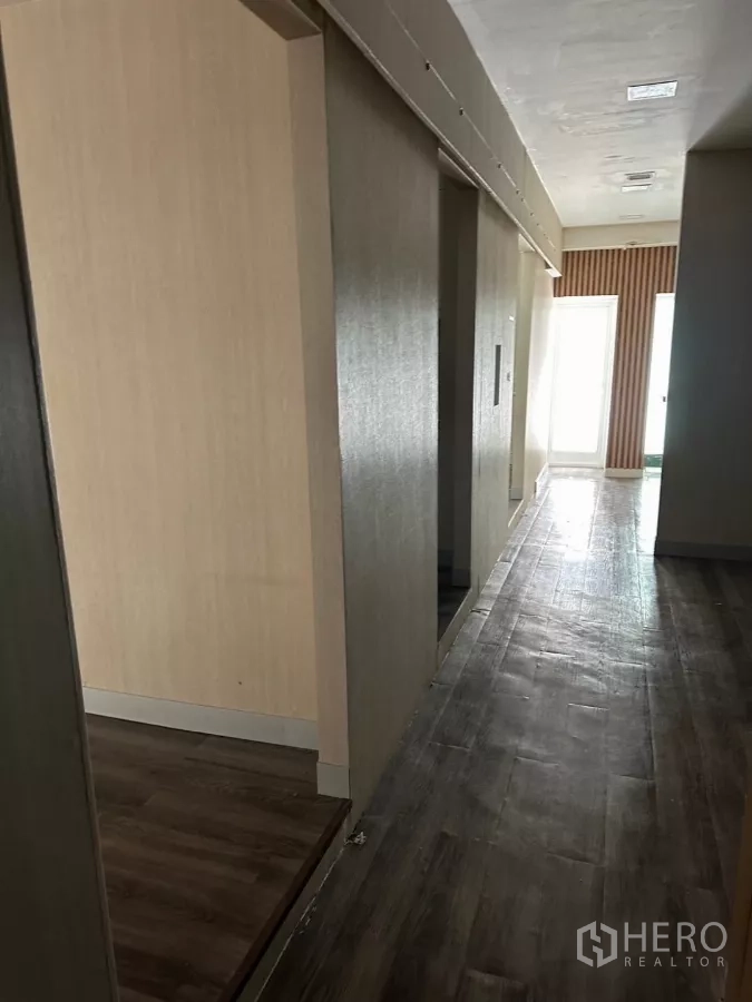 Shophouse for sale in Watthana, Bangkok - Partitioned corridor with wood vinyl flooring and daylight at the far end.
