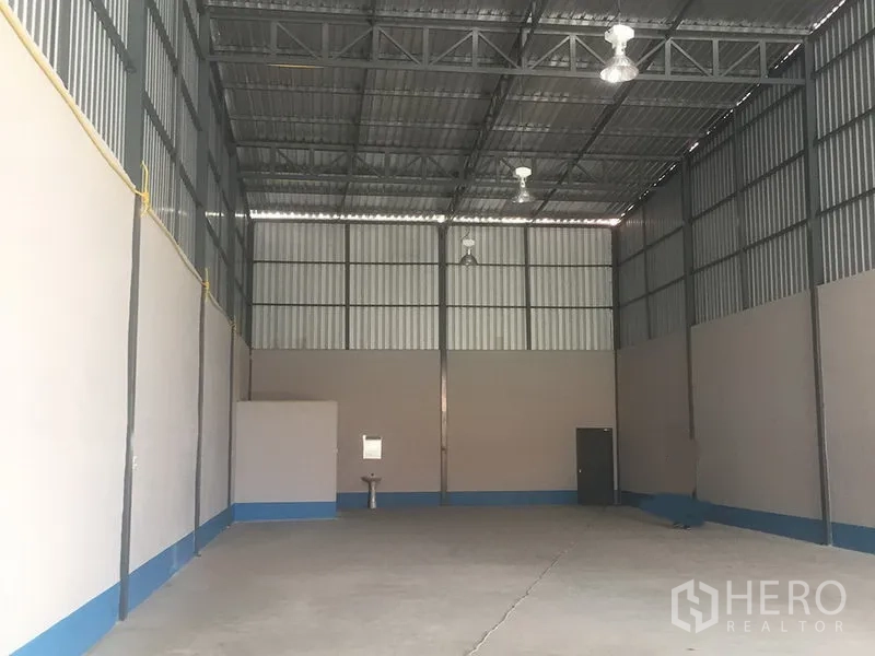 Warehouse for rent in Prawet, Bangkok - Spacious warehouse interior with high steel truss ceiling, hanging bay lights and smooth concrete floor.