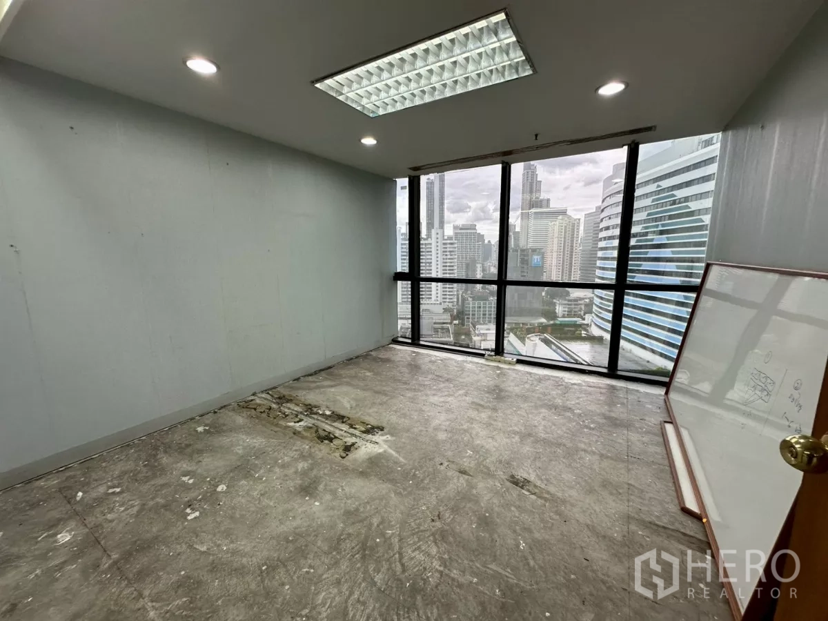 Office Space for rent in Khlong Toei, Bangkok - Private office with full-height windows and city view, whiteboard leaning against wall.