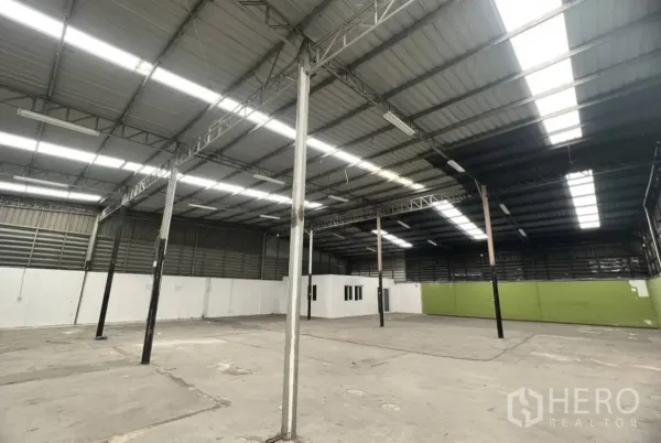 Warehouse for rent in Suan Luang, Bangkok - Spacious warehouse interior with high steel roof, skylight panels, and an internal office block.