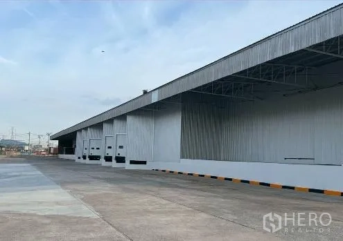 工厂 for rent in Si Racha, Chon Buri - 建筑侧面一排装卸门，设有雨棚与卡车停靠区。