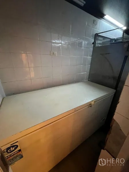零售空间 出租 - 商业储物区，白色卧式冰柜与瓷砖墙面。